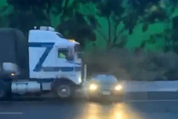 WATCH | Truck pushes car along wet freeway